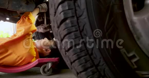 年轻漂亮的汽车修理工正躺在车下修理它视频的预览图