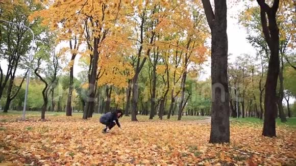 年轻女子在秋天公园里辗转落叶女戏树叶飘落视频的预览图