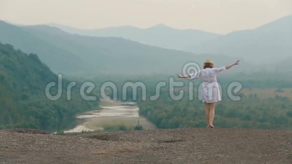 美丽的金发旅行者的后景举起双手慢慢地沿着山脉的边缘走着医生视频的预览图