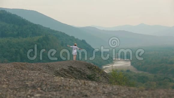 后景的金发游客愉快地在山的边缘跳舞欣赏风景视频的预览图
