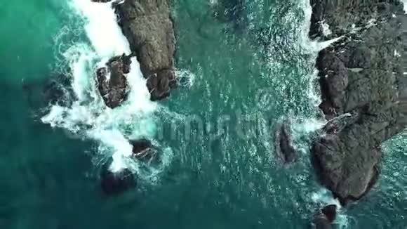 高空俯视海浪冲击到海滩附近的岩石无人机在危险的石头上射出海浪视频的预览图