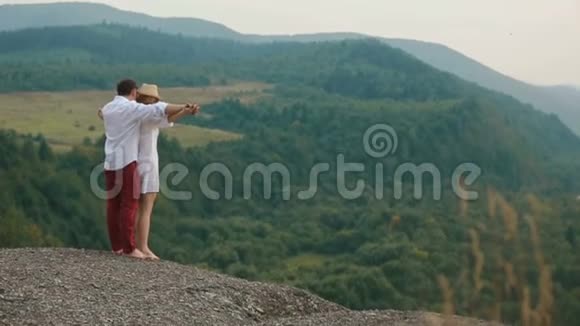 那个男人牵着那只美丽的金发女孩的手抱着她站在山的边缘视频的预览图