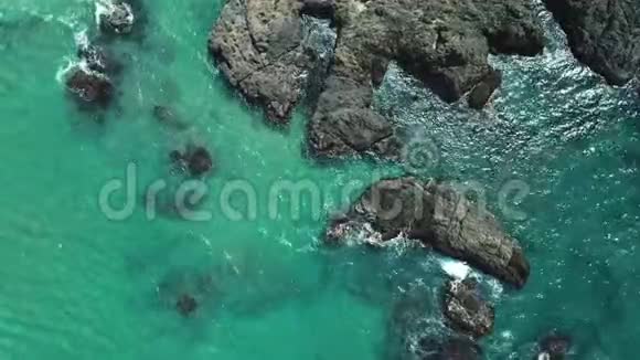高空俯视海浪冲击到海滩附近的岩石无人机在危险的石头上射出海浪视频的预览图