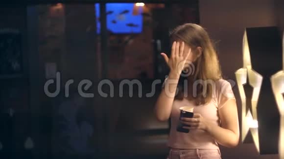 一个女孩带着咖啡和智能手机在夜城的肖像视频的预览图