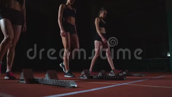年轻的女跑步运动员带着智能手表准备在跑道起跑线上冲刺视频的预览图