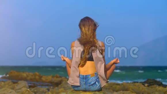 女子坐在莲花筒靠岸海景视频的预览图