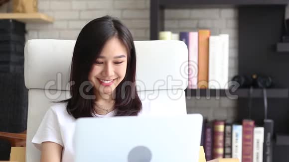 美丽的肖像亚洲年轻女子在网上工作微笑着开心地笑着坐在客厅视频的预览图