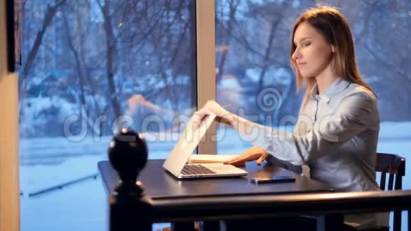 年轻女子打开笔记本电脑开始在全景窗口附近打字4K视频的预览图
