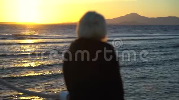 女人在海边看着五彩缤纷的日落视频的预览图