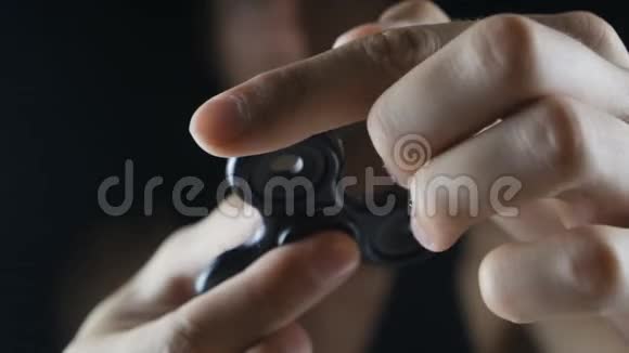 关闭旋转或坐立不安的手玩具在人的手黑色背景视频的预览图