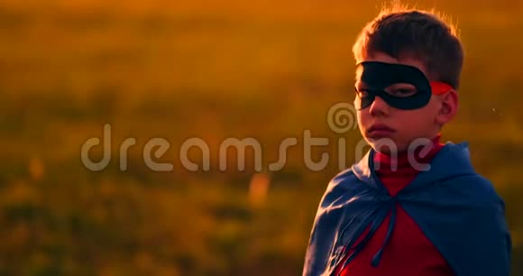 一个戴着面具的男孩和一个超级英雄在日落时在田野里的斗篷视频的预览图
