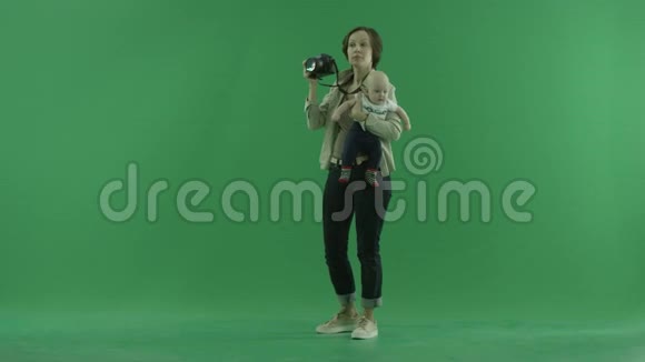 一个年轻的女人带着她的孩子在绿色屏幕的左手边拍照视频的预览图