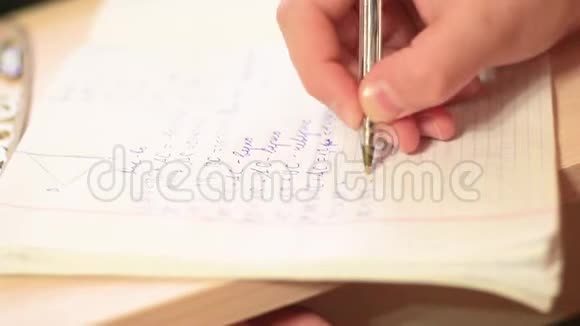 一个在笔记本上写特写的少年视频的预览图