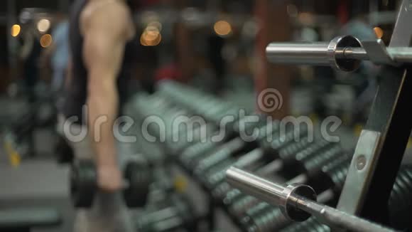 健身男子把大哑铃放回站立和离开满意的锻炼视频的预览图