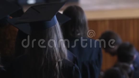 毕业日快乐戴着头巾和帽子的学生在等待文凭视频的预览图