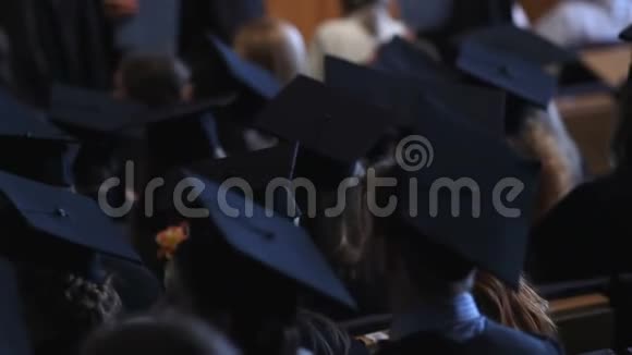 穿着学术服装坐在大学大厅的年轻人视频的预览图