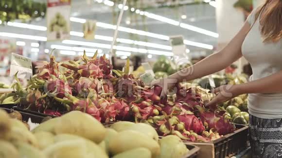 年轻漂亮的女人在超市为家人购买新鲜健康的火龙果选择手臂视频的预览图
