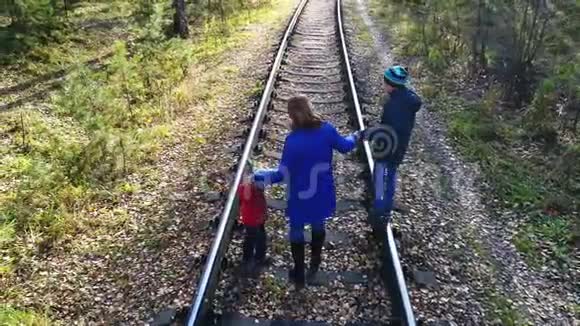 一个带着两个孩子在铁路上行走的小女孩秋天到户外散步视频的预览图