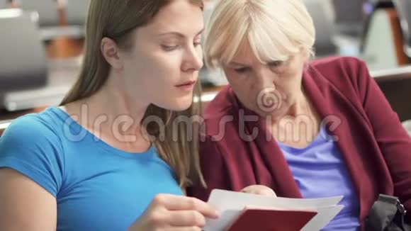 高级母亲和她的小女儿在机场航站楼检查护照和登机牌视频的预览图