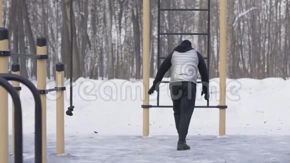 男子训练俯卧撑运动双腿在冬季运动场上抬起视频的预览图