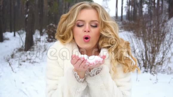 冬天的金发女郎在镜头里缓慢地吹着一把雪视频的预览图