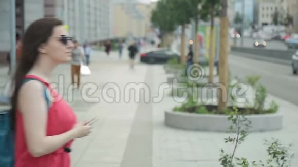 有电话的年轻女子在夏天花时间在街上视频的预览图