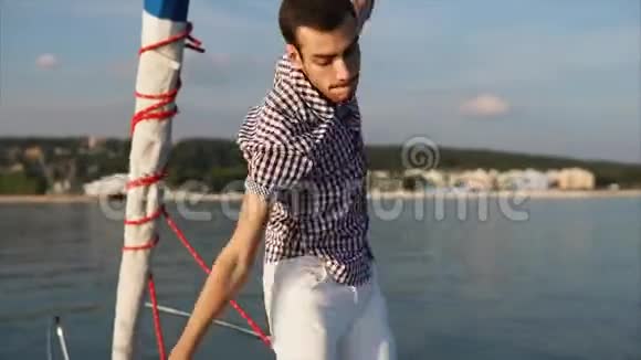 白天一个年轻而活跃的人在一艘游艇上跳舞这艘游艇跟着大海视频的预览图
