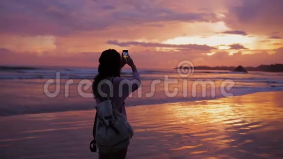 女孩在海边拍了一张美丽的日落照片视频的预览图