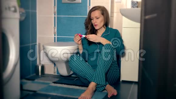 穿着睡衣的愤怒的年轻女人扔妊娠试验和浴室的衣柜视频的预览图