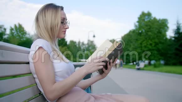 白种人年轻女性潮人在户外长凳上看书视频的预览图