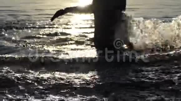 金发碧眼的男人在日落时分在湖里溅起水花视频的预览图