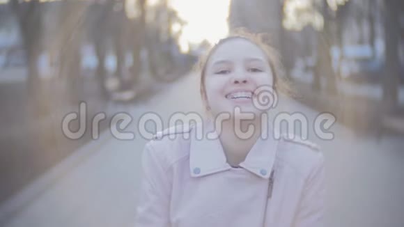 一个迷人的年轻女孩看着相机微笑的肖像近距离射击视频的预览图