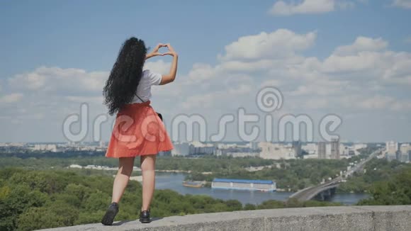 在城市背景下女孩用手臂展示了一颗心视频的预览图