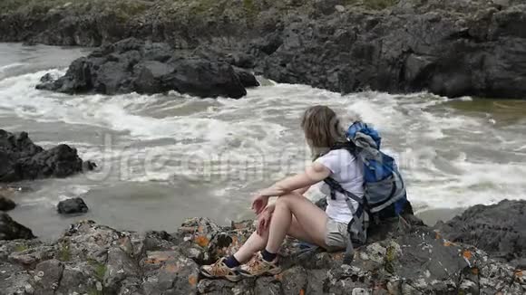 一个女孩坐在山河的岸边视频的预览图