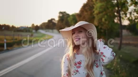 旅行者女人搭便车在阳光明媚的道路上行走视频的预览图