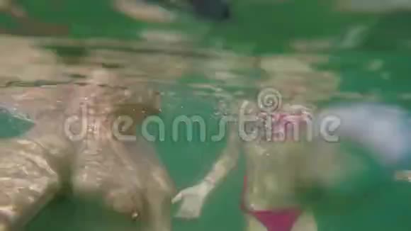 白种人的男人和女孩潜入海里在水下的镜头中挥动他们的手视频的预览图