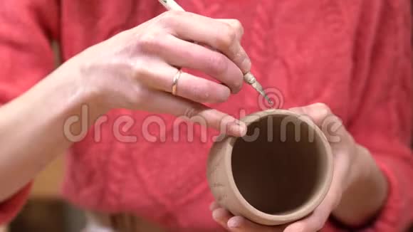 女陶工的特写用刀子在她手中的生泥杯上装饰视频的预览图