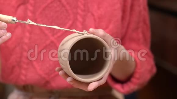 女性陶工的特写在生泥杯上放一块湿泥准备表面粘住手柄视频的预览图