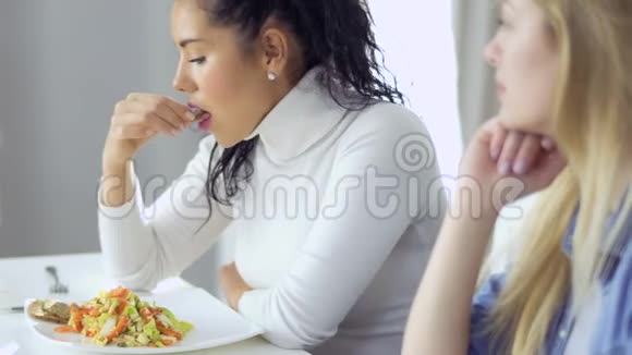 两个女孩正在厨房里吃沙拉和聊天视频的预览图
