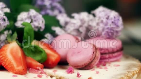 一份蛋糕上面点缀着马卡龙草莓和丁香花视频的预览图