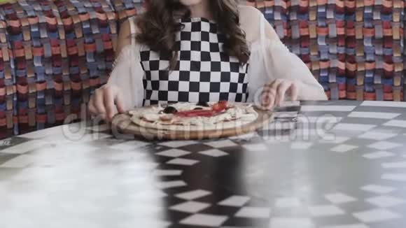 微笑的女孩在咖啡馆里旋转披萨对着镜头微笑视频的预览图