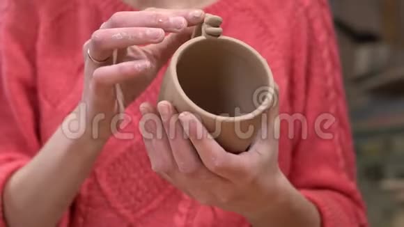 女陶匠的特写在她手中的生泥杯上做最后的触摸视频的预览图