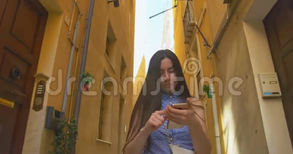 年轻女子早上在城里散步用智能手机女孩浏览互联网和某人发短信视频的预览图