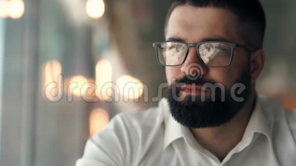 一个戴眼镜的留胡子的年轻人的特写一个戴眼镜看镜头的人的肖像视频的预览图