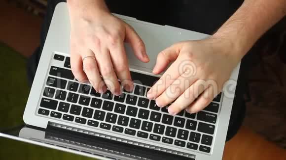 一个男人正在用笔记本电脑工作在键盘上键入文本笔记本电脑在我腿上从上面看视频的预览图