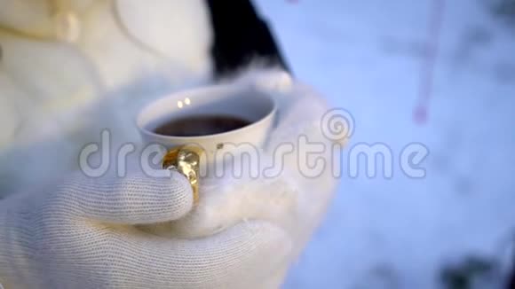 戴着白色手套的女性手拿着热气腾腾的白杯热咖啡或茶视频的预览图