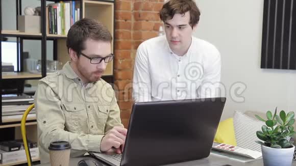 两位商人在办公室讨论商业问题年轻人看着笔记本电脑的屏幕视频的预览图