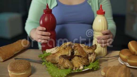 胖女人端着番茄酱蛋黄酱和烤鸡坐在桌上视频的预览图