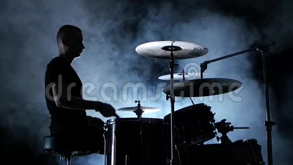 职业音乐家在鼓上演奏音乐烟熏背景侧视剪影背光慢动作视频的预览图
