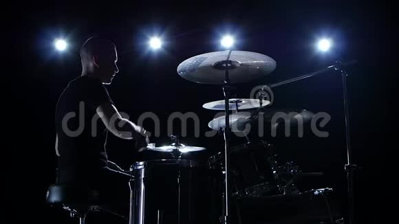 音乐家在鼓上演奏专业音乐黑色背景侧视背光剪影慢动作视频的预览图